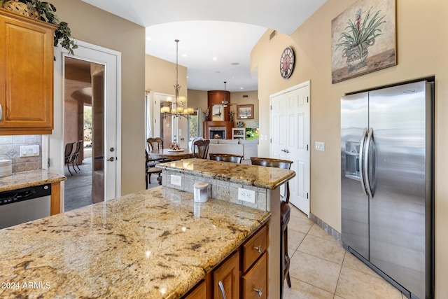 kitchen featuring decorative backsplash, light tile patterned floors, decorative light fixtures, light stone counters, and stainless steel appliances