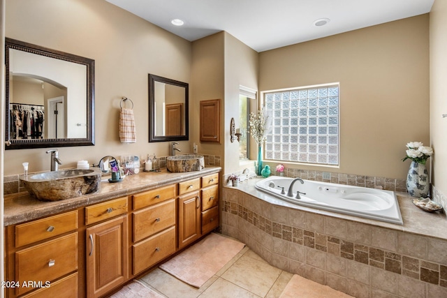 bathroom featuring tile patterned flooring, vanity, and a relaxing tiled tub