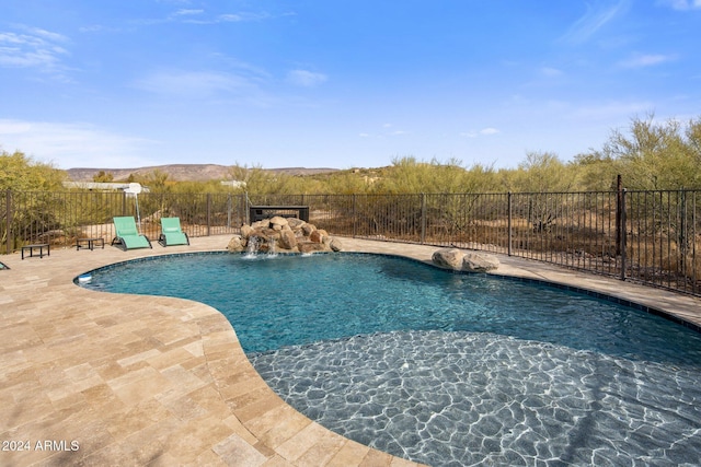 view of swimming pool with pool water feature, a mountain view, and a patio