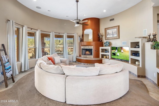 living room featuring a fireplace, a high ceiling, light colored carpet, and ceiling fan