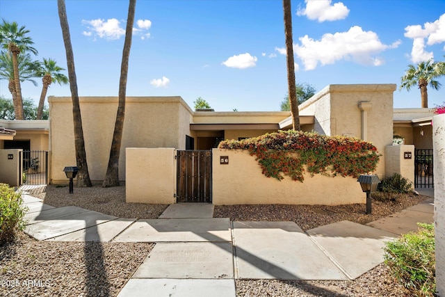 view of front of property with a fenced front yard, a gate, and stucco siding