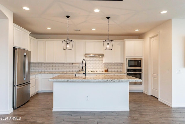 3023 W New River Dr, San Tan Valley, AZ 85144 - kitchen with white cabinetry, wood finished floors, under cabinet range hood, stainless steel appliances, and a kitchen island with sink