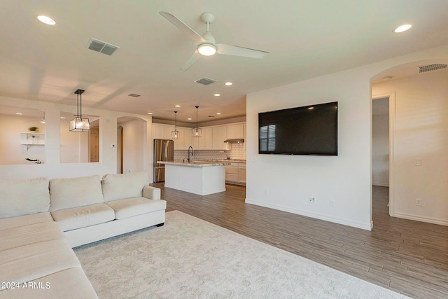 3023 W New River Dr, San Tan Valley, AZ 85144 - unfurnished living room featuring visible vents, wood finished floors, arched walkways, and a ceiling fan