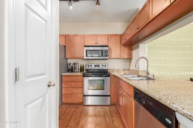 5345 E Van Buren St Unit 258, Phoenix, AZ 85008 - kitchen featuring light stone counters, a sink, brown cabinets, light wood-style flooring, and stainless steel appliances