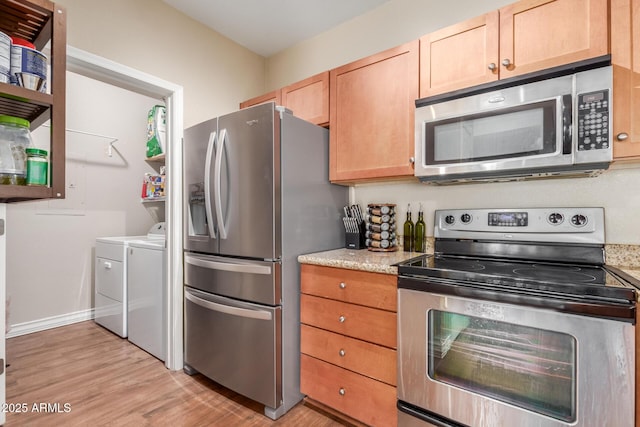 5345 E Van Buren St Unit 258, Phoenix, AZ 85008 - kitchen featuring washer and clothes dryer, light stone counters, light wood-style flooring, stainless steel appliances, and baseboards