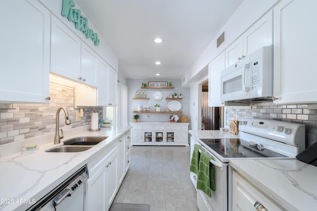 kitchen with sink, white appliances, light stone counters, white cabinets, and decorative backsplash