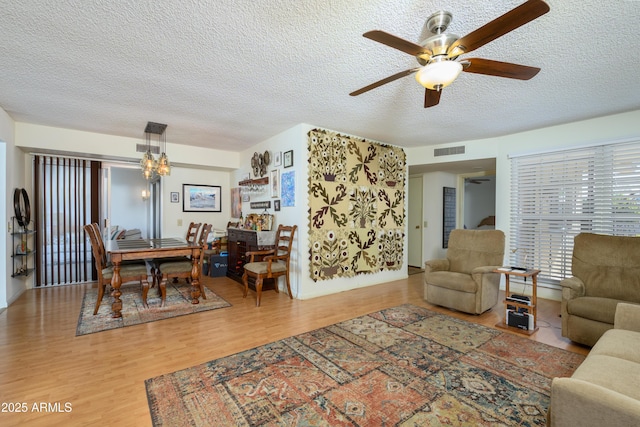 living room featuring ceiling fan, wood-type flooring, and a textured ceiling