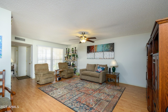 living room featuring ceiling fan, a textured ceiling, and light hardwood / wood-style flooring