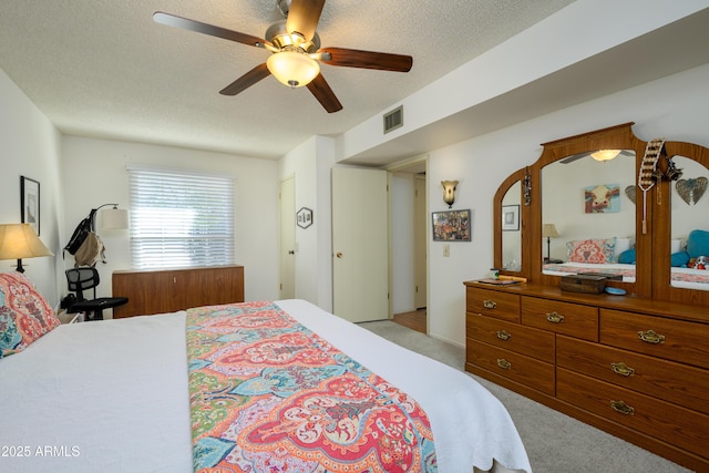 carpeted bedroom with ceiling fan and a textured ceiling