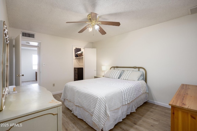 1454 W Capri Ave, Mesa, AZ 85202 - bedroom with light wood-type flooring, a textured ceiling, a ceiling fan, a closet, and a walk in closet