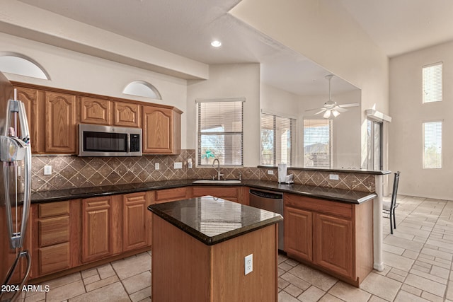 kitchen featuring sink, ceiling fan, appliances with stainless steel finishes, tasteful backsplash, and a center island