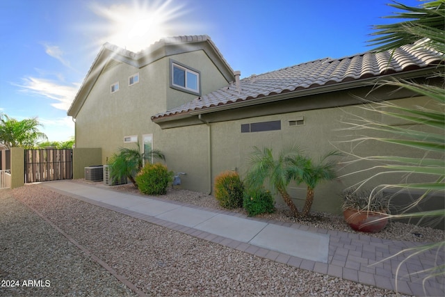 view of property exterior featuring a tile roof, a gate, fence, and stucco siding