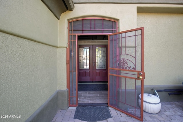 view of exterior entry featuring french doors and stucco siding