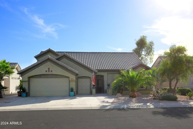 view of front of home with driveway, a tiled roof, an attached garage, and stucco siding