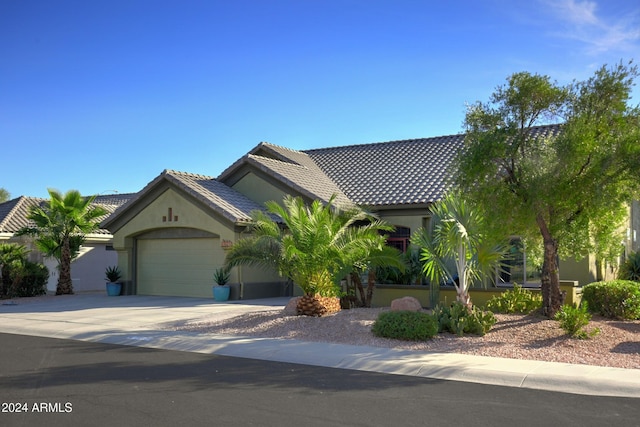 view of front facade featuring an attached garage, a tiled roof, concrete driveway, and stucco siding