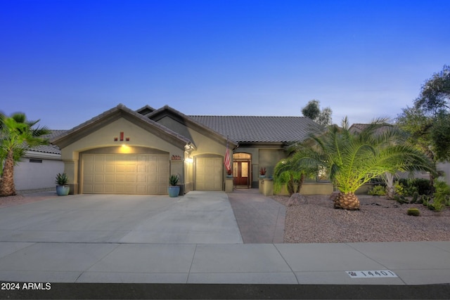 view of front facade with a garage, a tile roof, driveway, and stucco siding