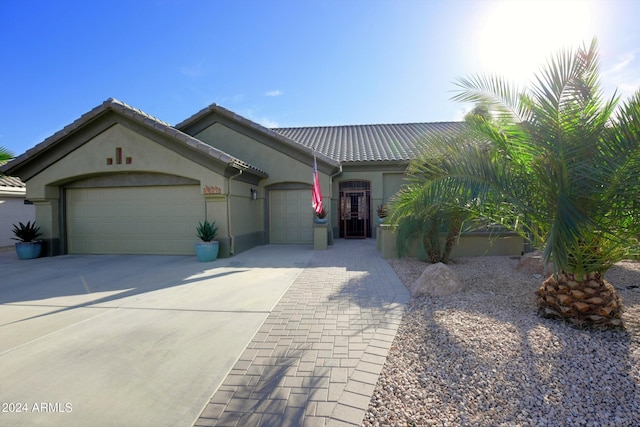 view of front of property with driveway, a tiled roof, an attached garage, and stucco siding