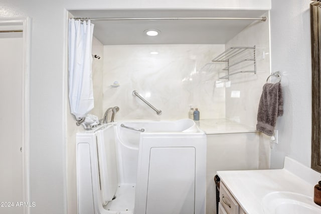 bathroom featuring a bathtub, a shower with curtain, washer / clothes dryer, and vanity