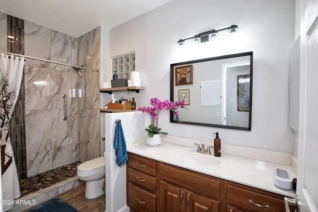 bathroom featuring toilet, tiled shower, and vanity