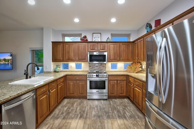 kitchen featuring brown cabinetry, light wood-style floors, stainless steel appliances, and a sink