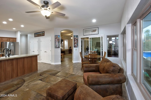 living room with baseboards, arched walkways, a ceiling fan, and recessed lighting