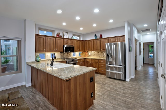 kitchen featuring stainless steel appliances, a peninsula, a sink, visible vents, and brown cabinets