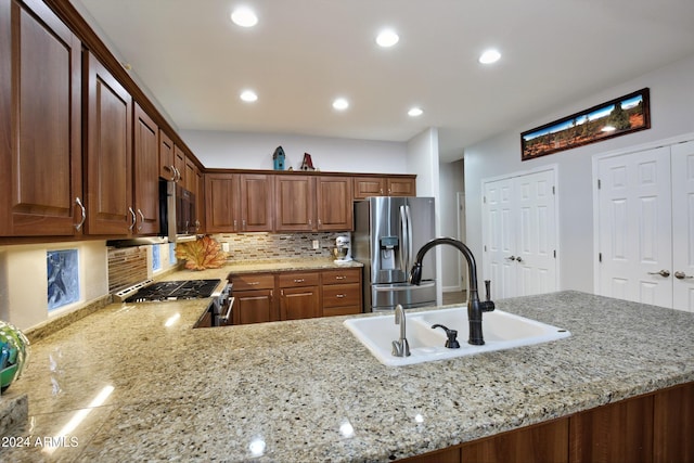 kitchen featuring appliances with stainless steel finishes, a sink, and light stone counters