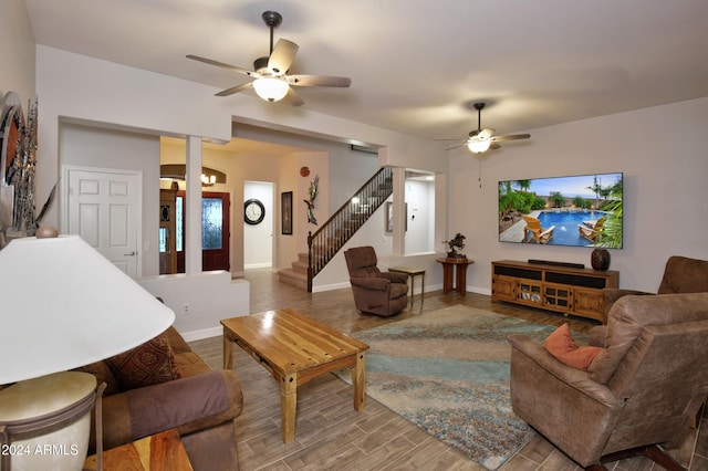 living room featuring wood finished floors, ceiling fan, baseboards, and stairs