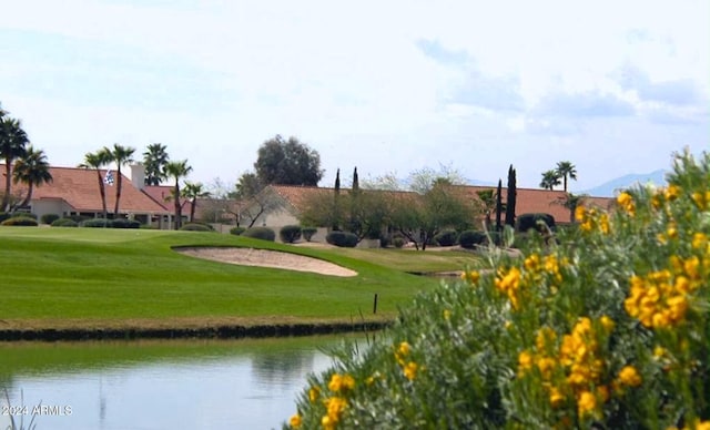 view of home's community with a yard, a water view, and view of golf course