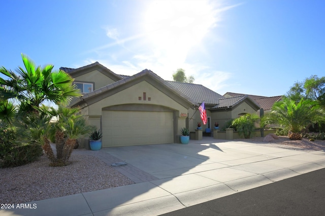 view of front facade featuring driveway, a tiled roof, an attached garage, and stucco siding