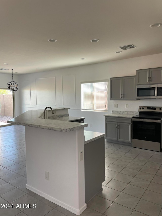 kitchen featuring gray cabinetry, appliances with stainless steel finishes, light tile patterned flooring, and decorative light fixtures