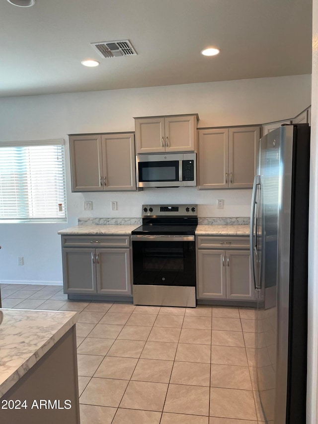 kitchen with gray cabinets, appliances with stainless steel finishes, and light tile patterned floors