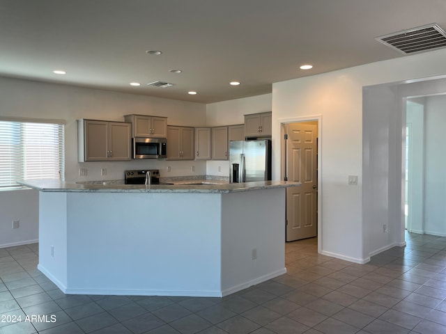 kitchen with gray cabinetry, stainless steel appliances, sink, light stone countertops, and light tile patterned flooring