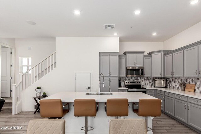 286 E Raleigh Dr, Chandler, AZ 85286 - kitchen featuring gray cabinetry, stainless steel appliances, a sink, decorative backsplash, and light wood finished floors