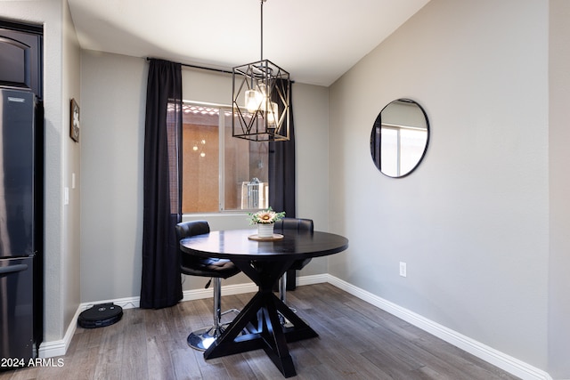 dining area featuring dark wood-type flooring and an inviting chandelier