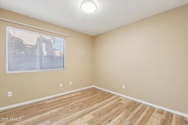 spare room featuring baseboards and light wood-style flooring