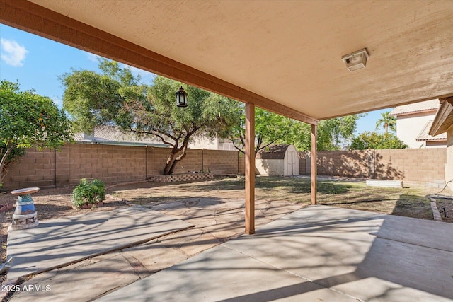 view of patio featuring a storage unit, a fenced backyard, and an outdoor structure