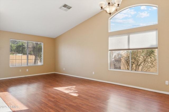 spare room with visible vents, baseboards, a notable chandelier, and wood finished floors