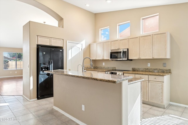 kitchen featuring light stone counters, stainless steel appliances, high vaulted ceiling, and a sink