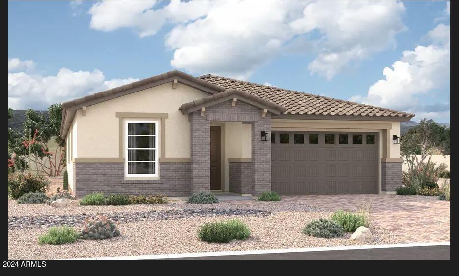 mediterranean / spanish house with brick siding, a tiled roof, an attached garage, decorative driveway, and stucco siding