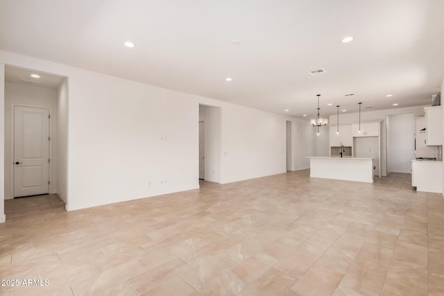 unfurnished living room featuring a notable chandelier, visible vents, and recessed lighting