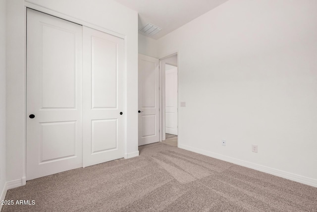 unfurnished bedroom featuring carpet flooring, baseboards, a closet, and visible vents
