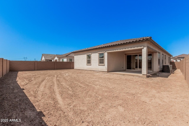 back of house with stucco siding, a fenced backyard, a tiled roof, central AC unit, and a patio area