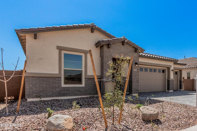 view of front of property with a tiled roof, stucco siding, fence, and an attached garage