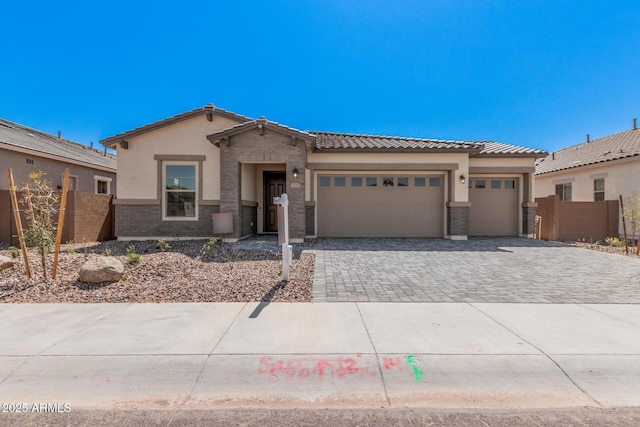 view of front of home with a tile roof, stucco siding, fence, an attached garage, and decorative driveway