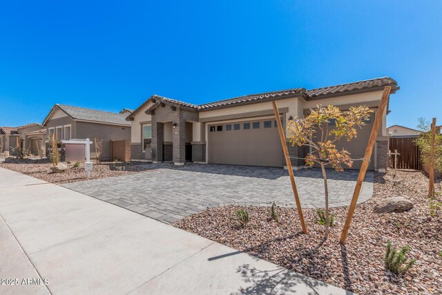 mediterranean / spanish-style home featuring a tile roof, decorative driveway, stucco siding, and an attached garage