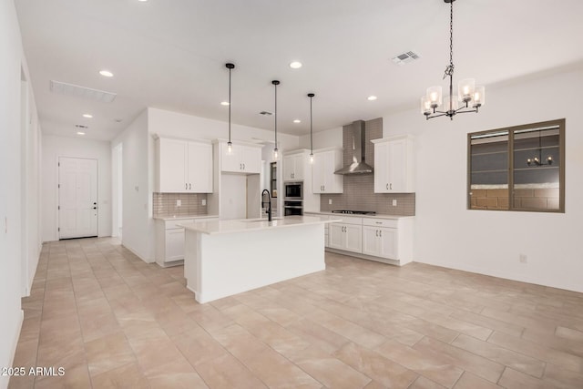 kitchen with light countertops, decorative backsplash, visible vents, appliances with stainless steel finishes, and wall chimney exhaust hood