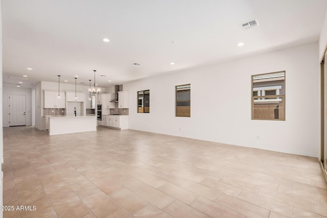 unfurnished living room with visible vents, recessed lighting, and an inviting chandelier