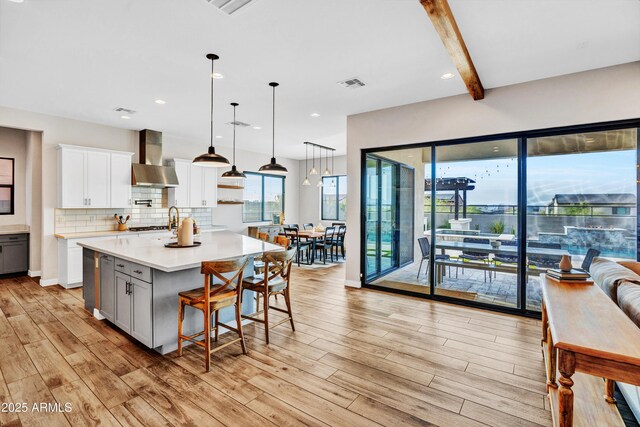 826 E Buist Ave, Phoenix, AZ 85042 - kitchen with wall chimney range hood, light countertops, light wood-type flooring, decorative backsplash, and a spacious island
