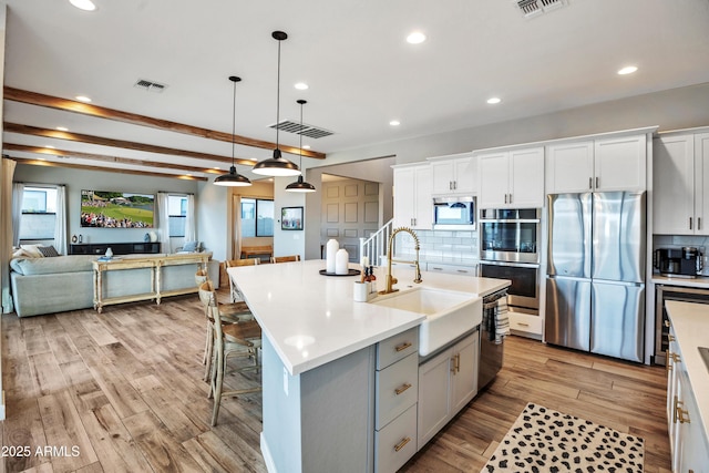 826 E Buist Ave, Phoenix, AZ 85042 - kitchen with appliances with stainless steel finishes, a sink, backsplash, light wood-style floors, and light countertops